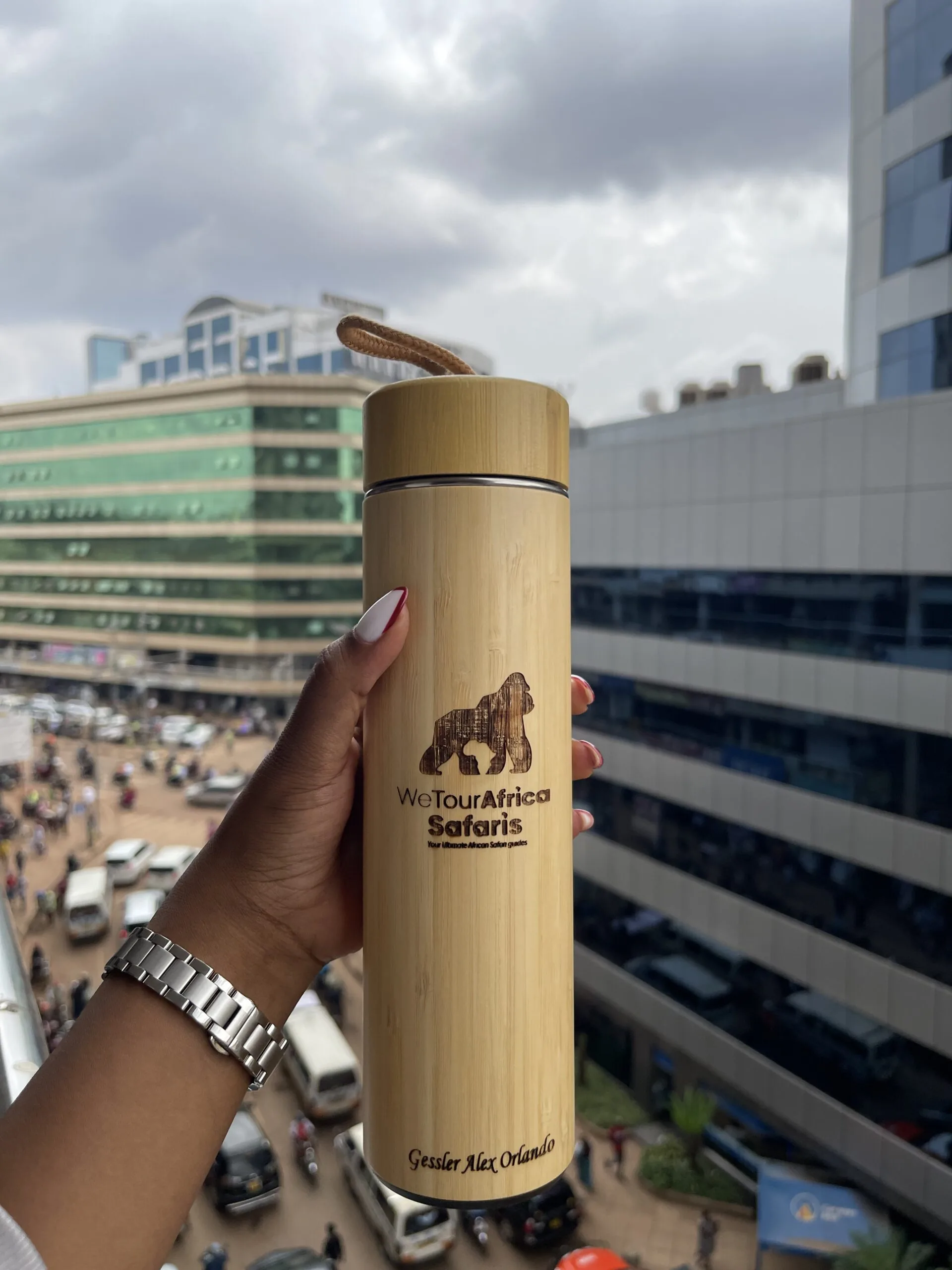 A bamboo bottle engraved with a gorilla, held up over the city