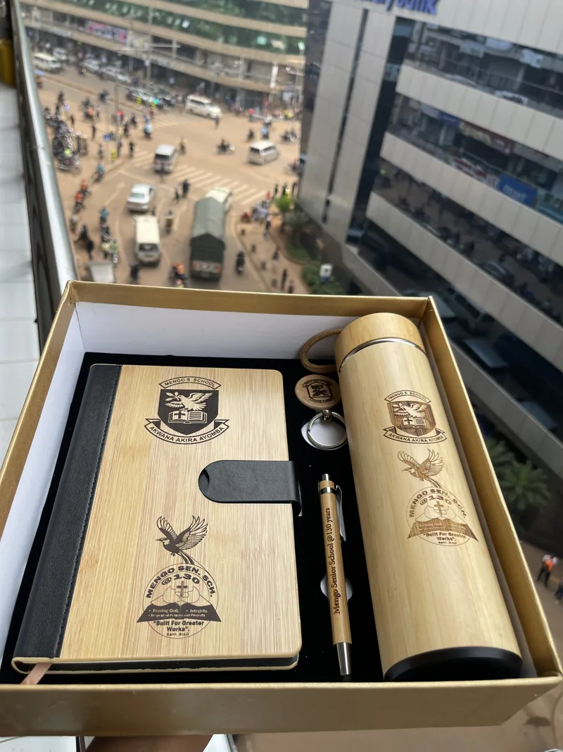 An open gift box with an engraved notebook, bottle and pen